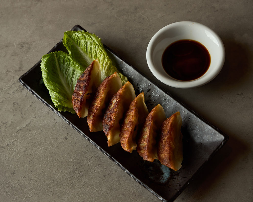 Overhead view of pan-fried pork gyoza with dipping sauce